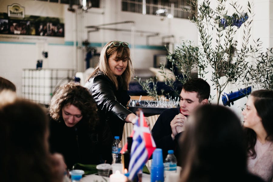 woman pouring olive oil in glass from the bottle at Konstas Olive Tours and tourits tasting it